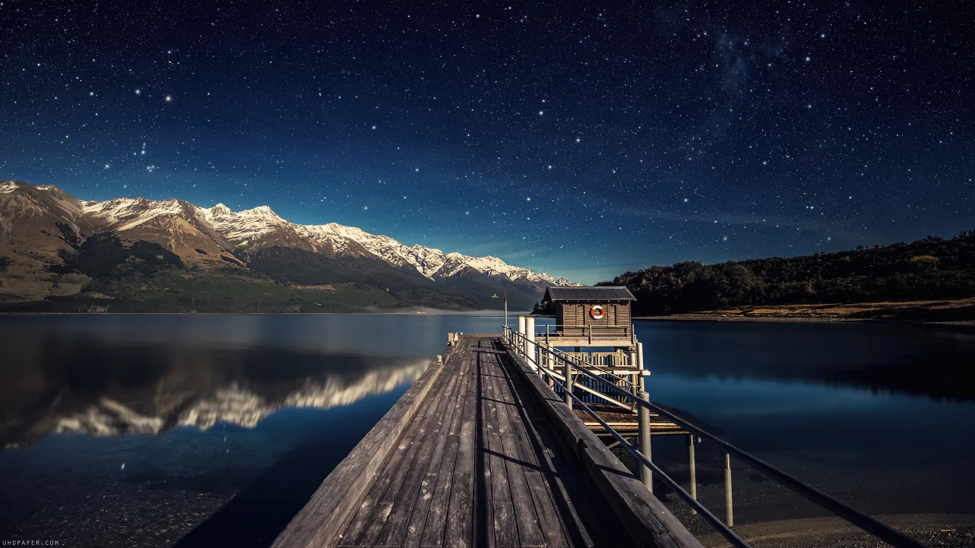 Estrellas en el cielo nocturno, lago y puente en nueva zelanda